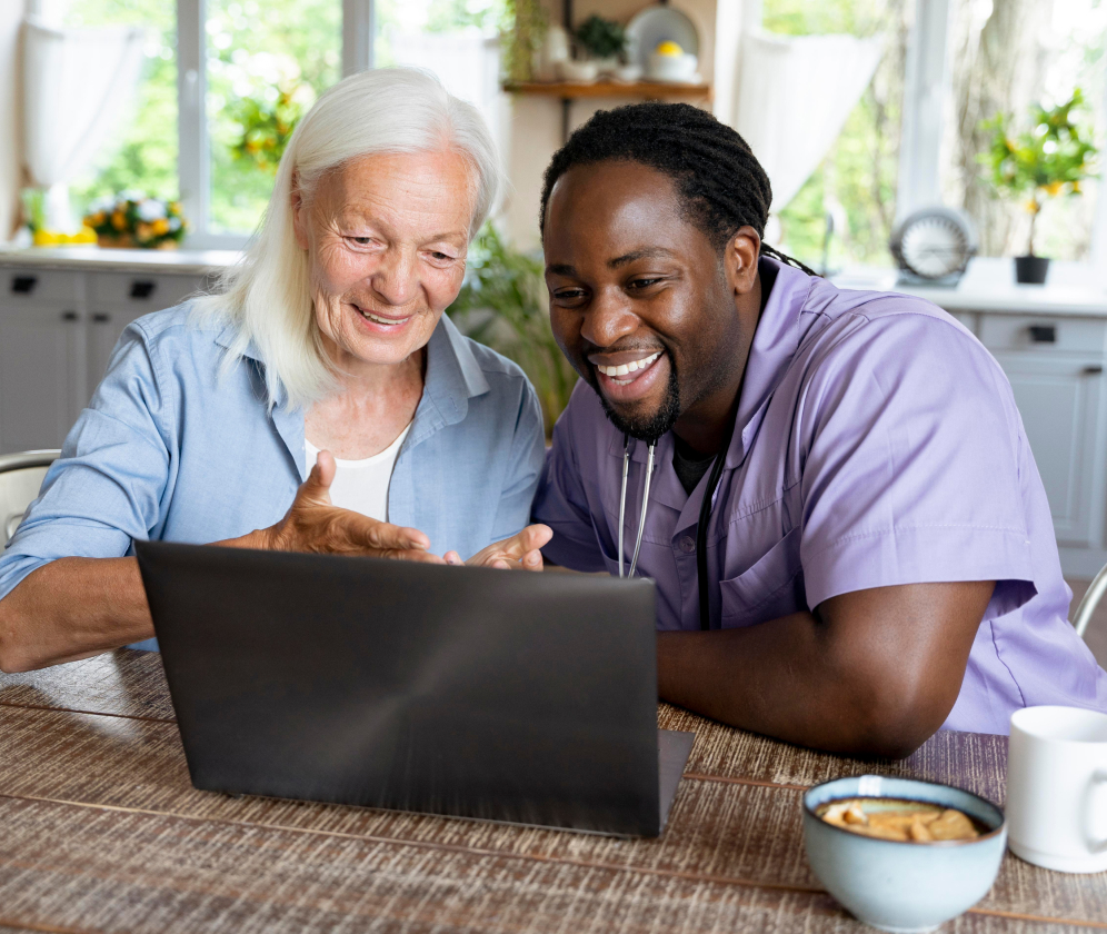 Social worker looking at laptop with senior woman